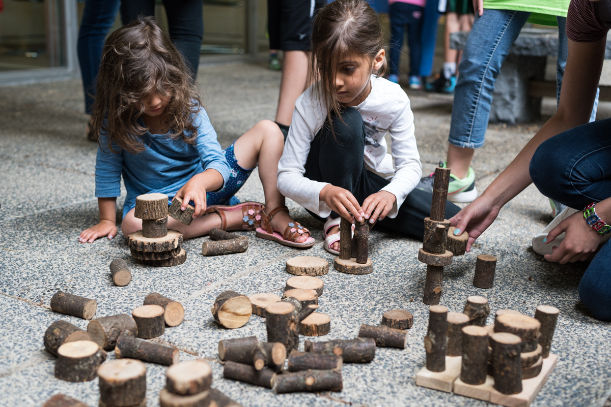 During Nature Play, children are free to play with Tree Blocks that are purchased beforehand. Children sitting on the ground, playing with Tree Blocks