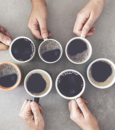 hands holding cups of black coffee