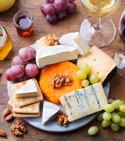 assortment of cheese fruit and wine on a wooden surface