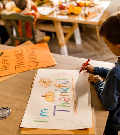 young boy drawing a colorful thankfulness poster