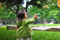 A young girl plays with bubbles in a park