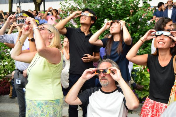 Photograph of people outside looking at the solar eclipse with eclipse glasses