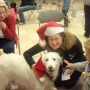 White dog wearing santa hat with owner and child White dog wearing santa hat with owner and child