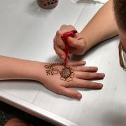 Henna artist Lauren Grover is creating a design on the hand of a participant.
