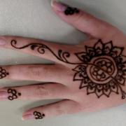 A participant shows off their hand with a completed henna design.