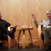 Nima Arkani-Hamed and Freeman Dyson sit next to each other while talking to a large crowd.