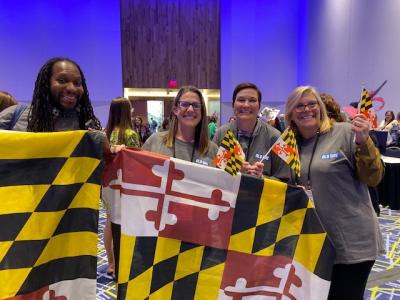 Four conference attendees holding the Maryland state flag 