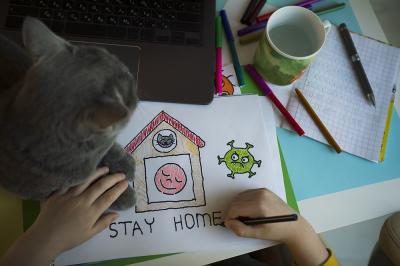 Photo of a child drawing a picture titled "Stay home"