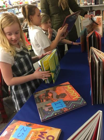 Students peruse books on a table