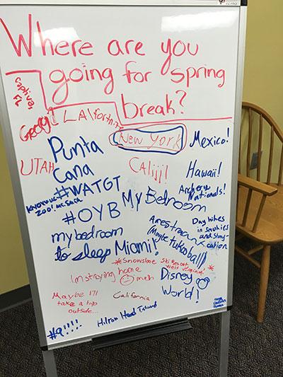 Writing on a whiteboard asking, "Where are you going for spring break?" with responses