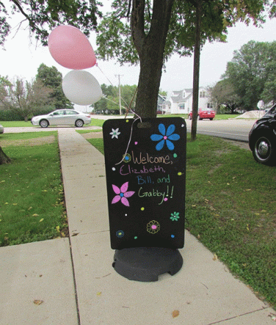 Sidewalk sign with balloons tied to it