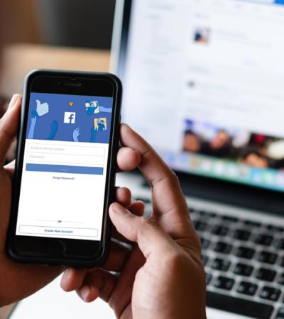 Photo of an iPhone screen and laptop logged onto Facebook