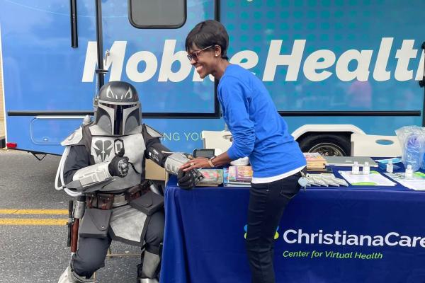 A photographer of a person in front of the Mobile Health vehicle in the library parking lot.