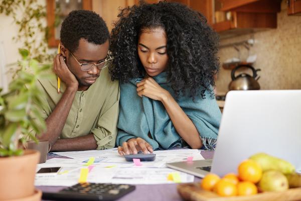 Photo of two people looking at financial papers with a calculator.