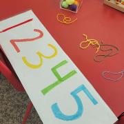 Photograph of a Manipulation Station table with large colorful paper numbers 1 2 3 4 5
