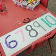 Photograph of a Manipulation Station table with large colorful paper numbers 6 7 8 9 10