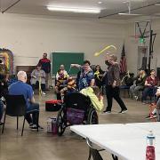 People gathered in a circle playing with ribbons