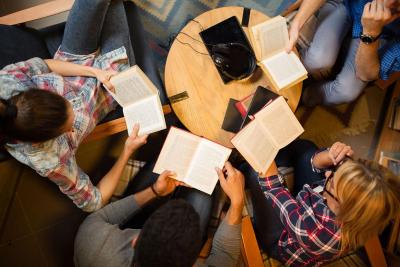 Four people sitting around a table with open books